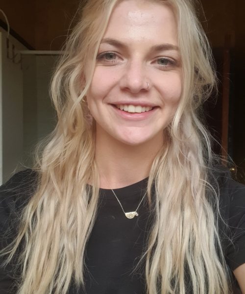 An early childhood educator with long blonde hair wearing a black shirt, smiling.